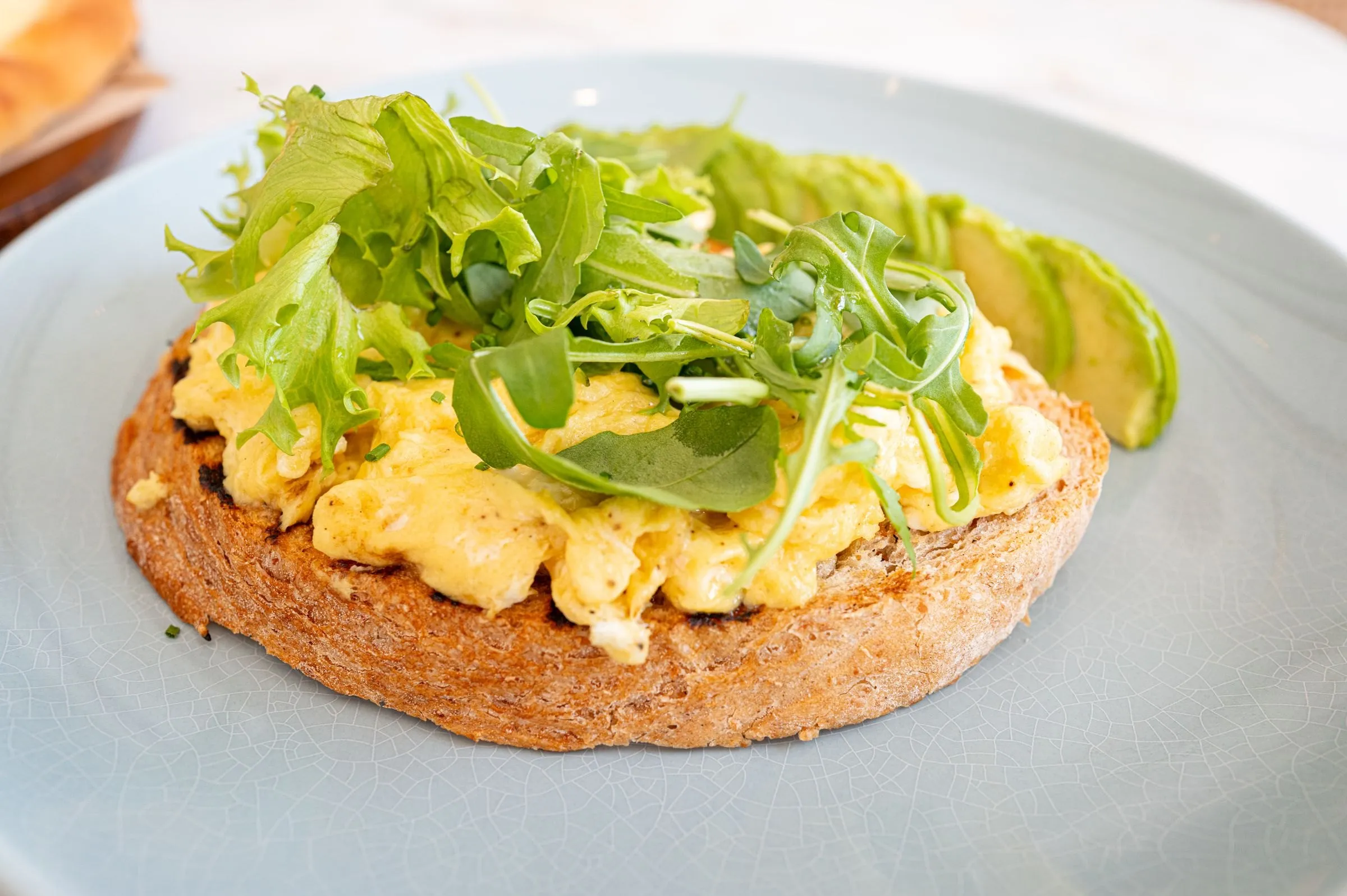 Œufs brouillés sur pain grillé, roquette et avocat
