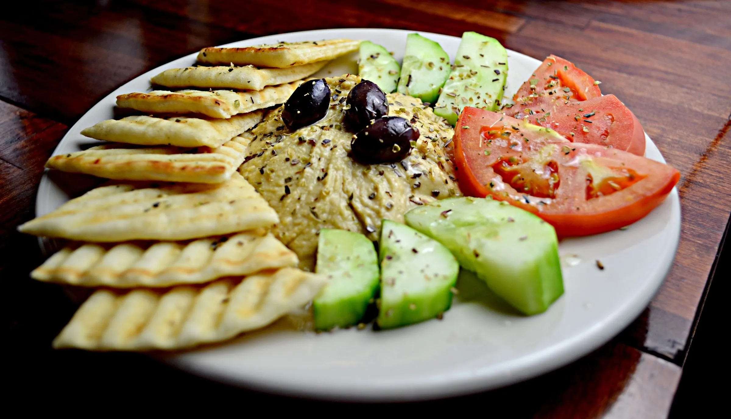 Assiette de houmous, pain pita, tomates, concombre et olives